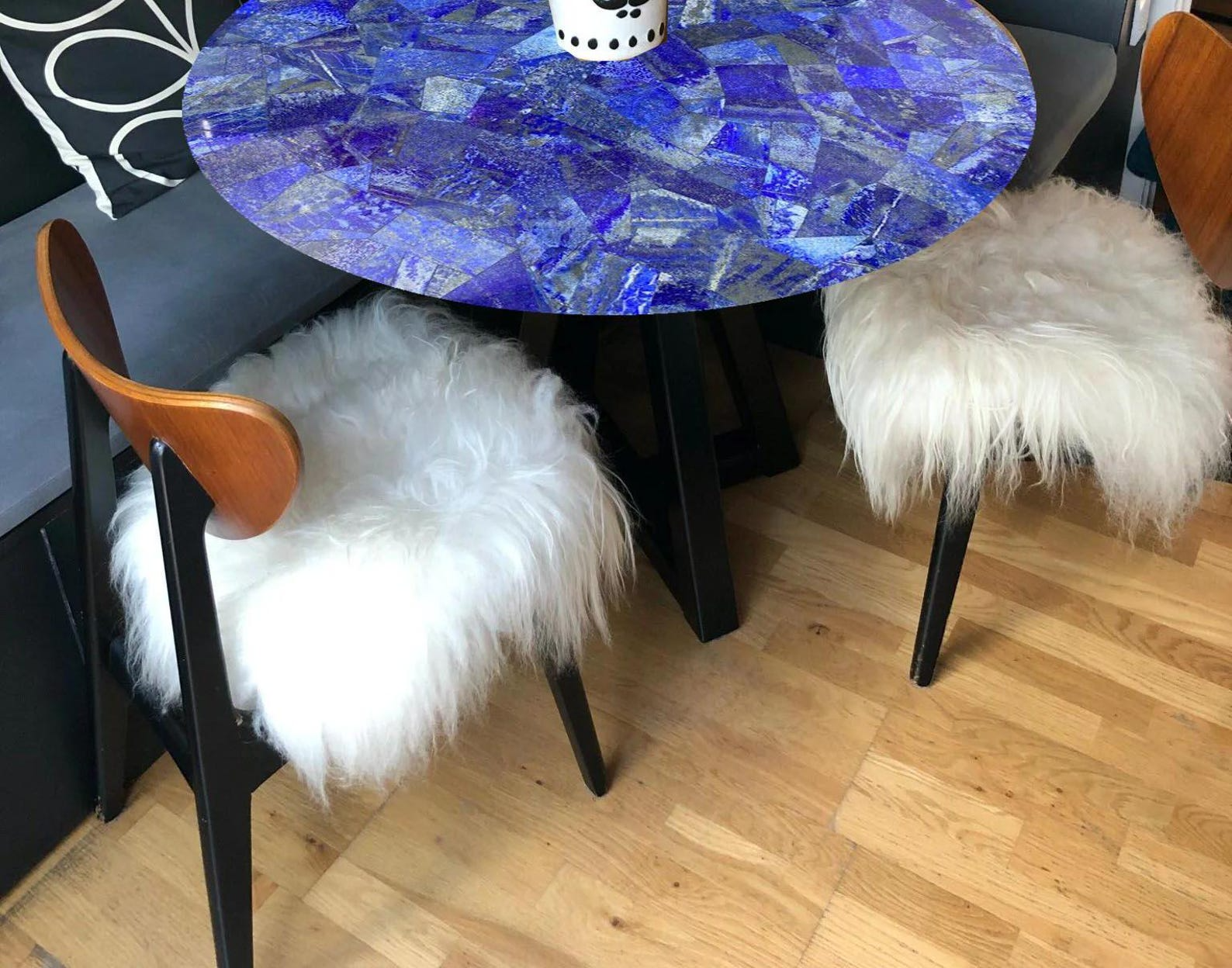 Stunning round blue lapis-inspired table with a glossy mosaic design, featuring vibrant yellow floral decor in a unique vase.